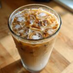 Close-up of a tall glass filled with a refreshing Iced Lavender Latte, showing layers of milk and coffee over ice.