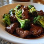 Close-up of tender chunks of beef and bright green broccoli florets coated in rich brown sauce from Instant Pot Beef and Broccoli.