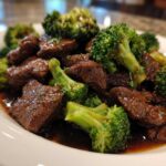 Close-up of tender chunks of beef coated in dark sauce served with bright green broccoli florets in Instant Pot Beef and Broccoli.