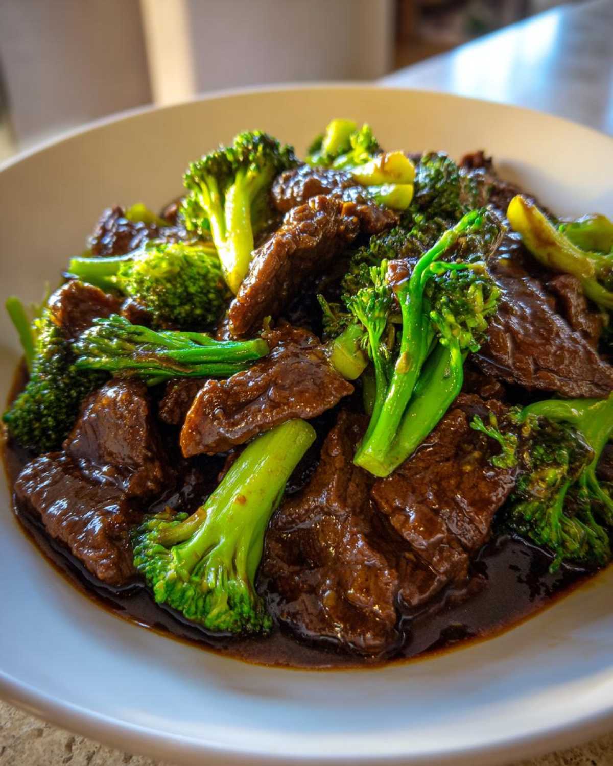 A close-up shot of tender slices of beef coated in dark sauce mixed with bright green broccoli florets, ready to eat Instant Pot Beef and Broccoli.