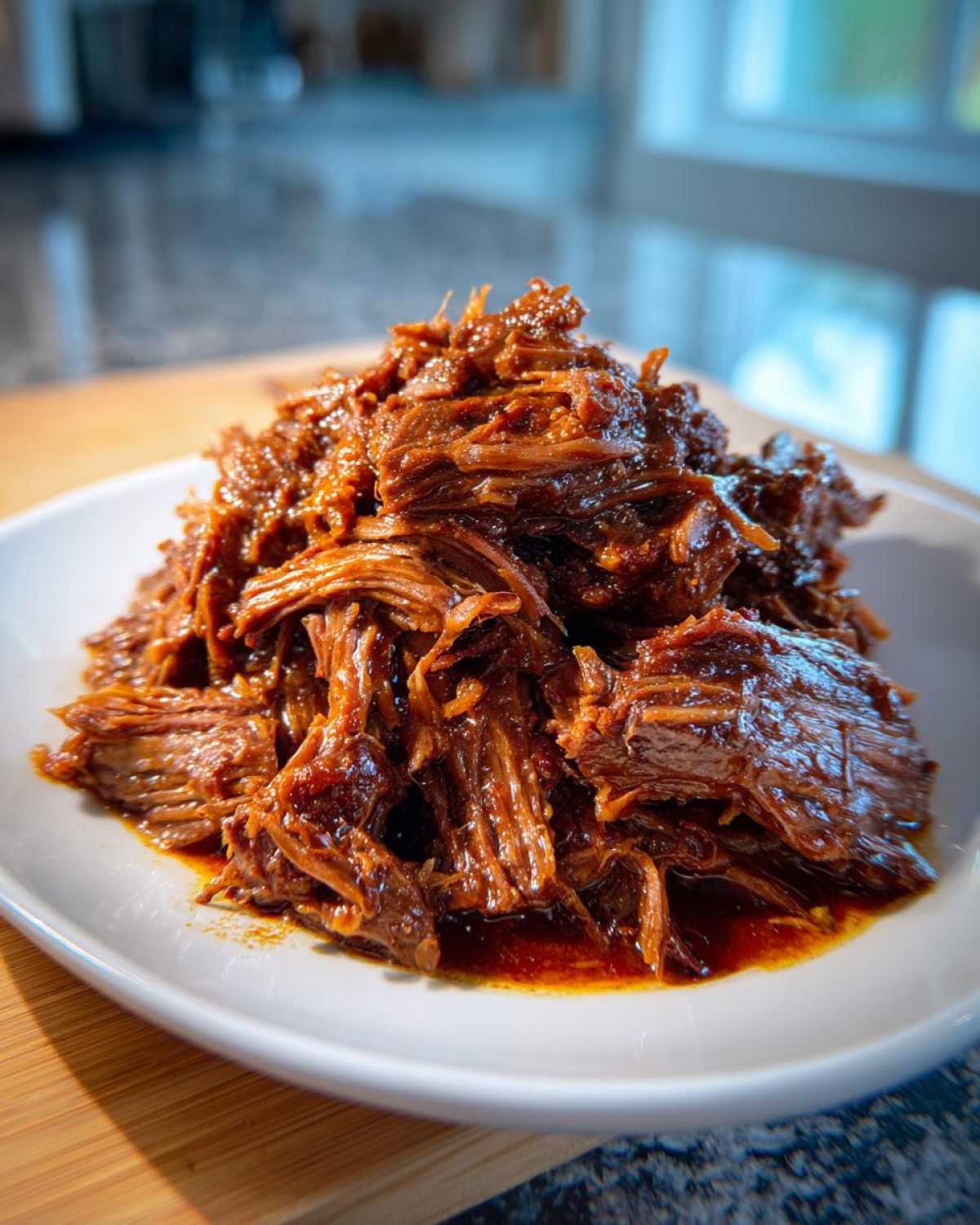 A close-up of rich, shredded Instant Pot Beef Barbacoa piled high on a white plate.