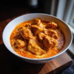 Close-up of succulent chicken pieces swimming in a rich, creamy orange sauce of Instant Pot Butter Chicken.