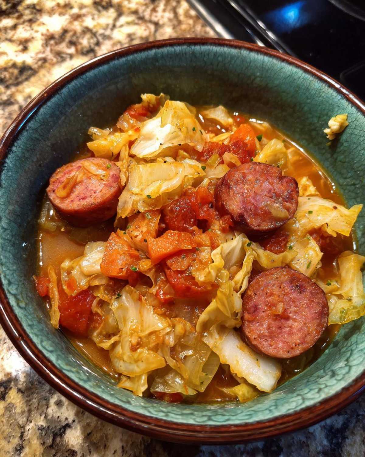 Close-up of a bowl of Instant Pot Cabbage and Sausage Soup with chunks of smoked sausage and cabbage.