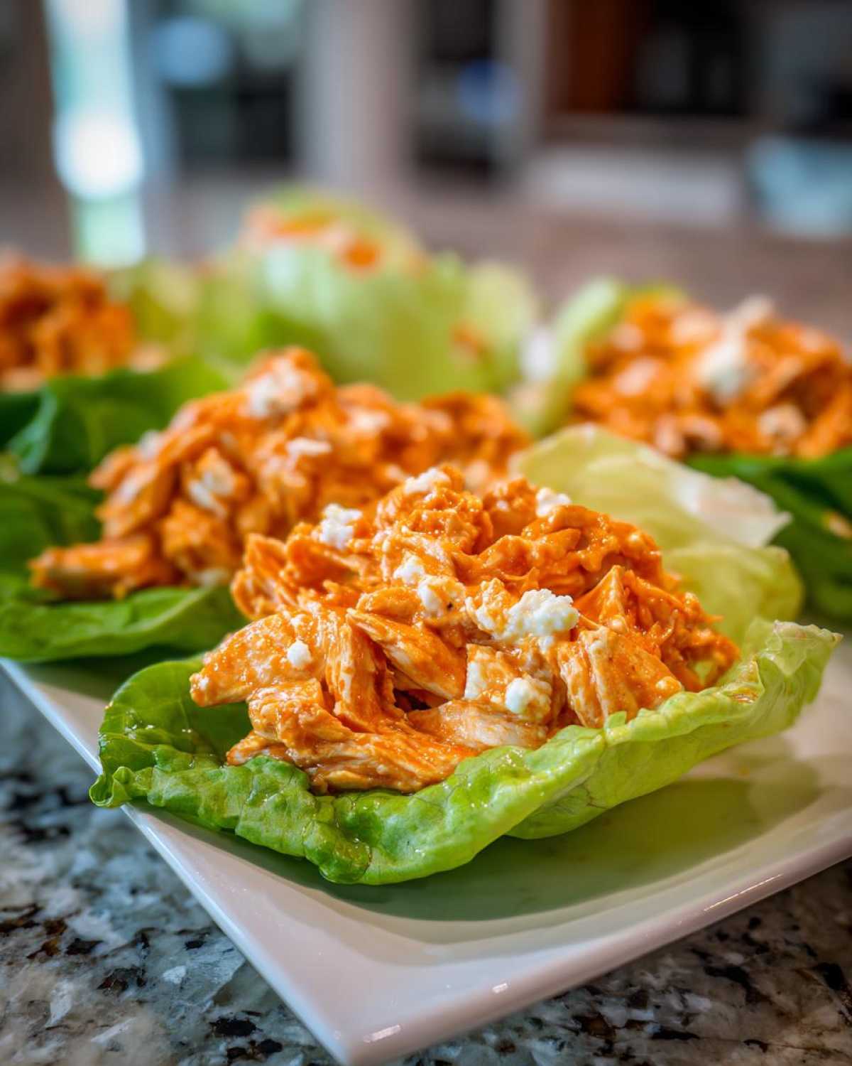 Close-up of Keto Buffalo Chicken Lettuce Wraps filled with shredded orange buffalo chicken and crumbled white cheese.