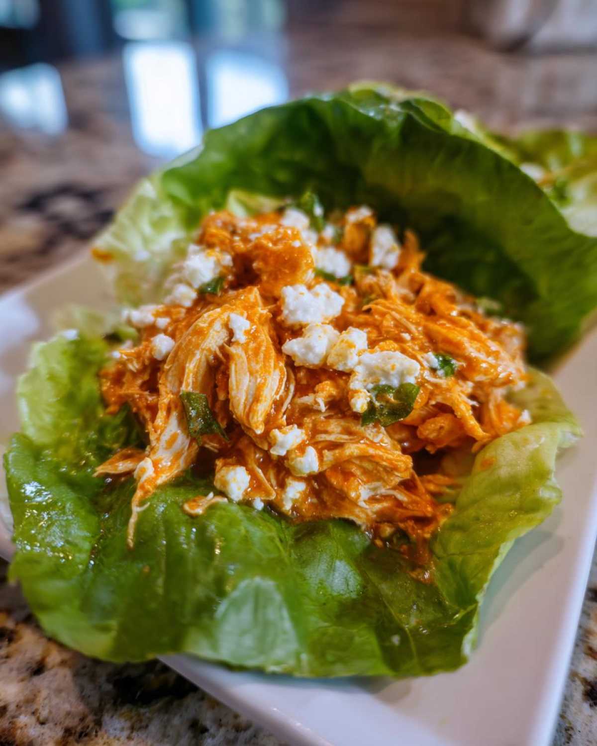 A single serving of Keto Buffalo Chicken Lettuce Wraps filled with shredded buffalo chicken and crumbled cheese.