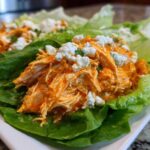 Close-up of Keto Buffalo Chicken Lettuce Wraps filled with shredded orange buffalo chicken and topped with crumbled blue cheese.