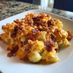 Close-up of Keto Cauliflower Mac and Cheese topped with crispy bacon bits and a crunchy topping.
