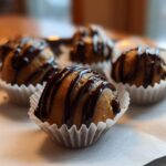 A close-up of several Keto Chocolate Peanut Butter Fat Bombs drizzled with dark chocolate.