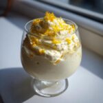 A serving of light, fluffy Keto Lemon Cheesecake Mousse topped with bright yellow lemon zest.