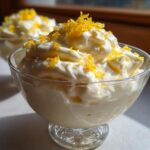 Close-up of a glass dish filled with fluffy Keto Lemon Cheesecake Mousse topped with bright yellow lemon zest.