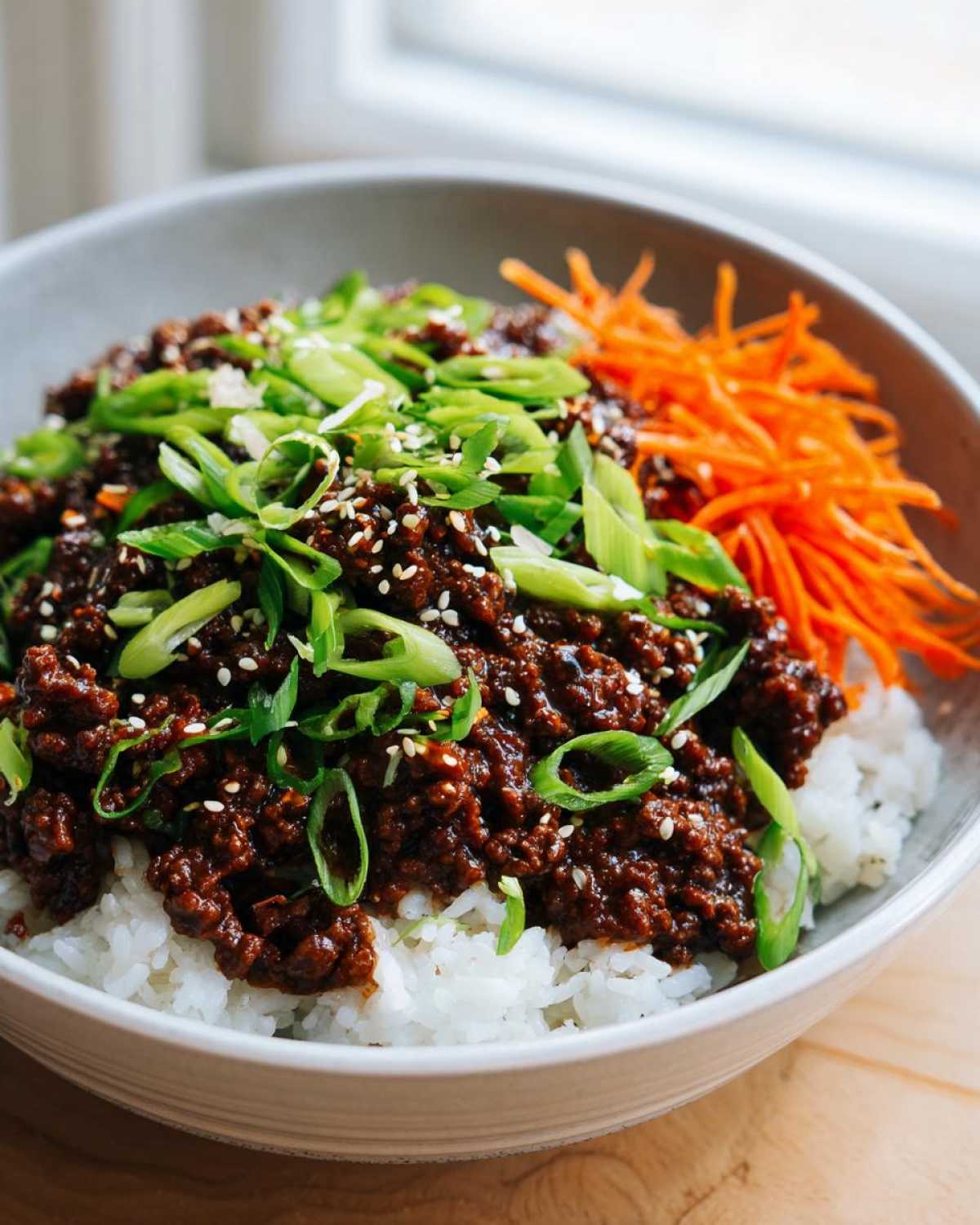 Close-up of Korean Ground Beef Bulgogi Bowls featuring savory ground beef over white rice, topped with green onions and sesame seeds.