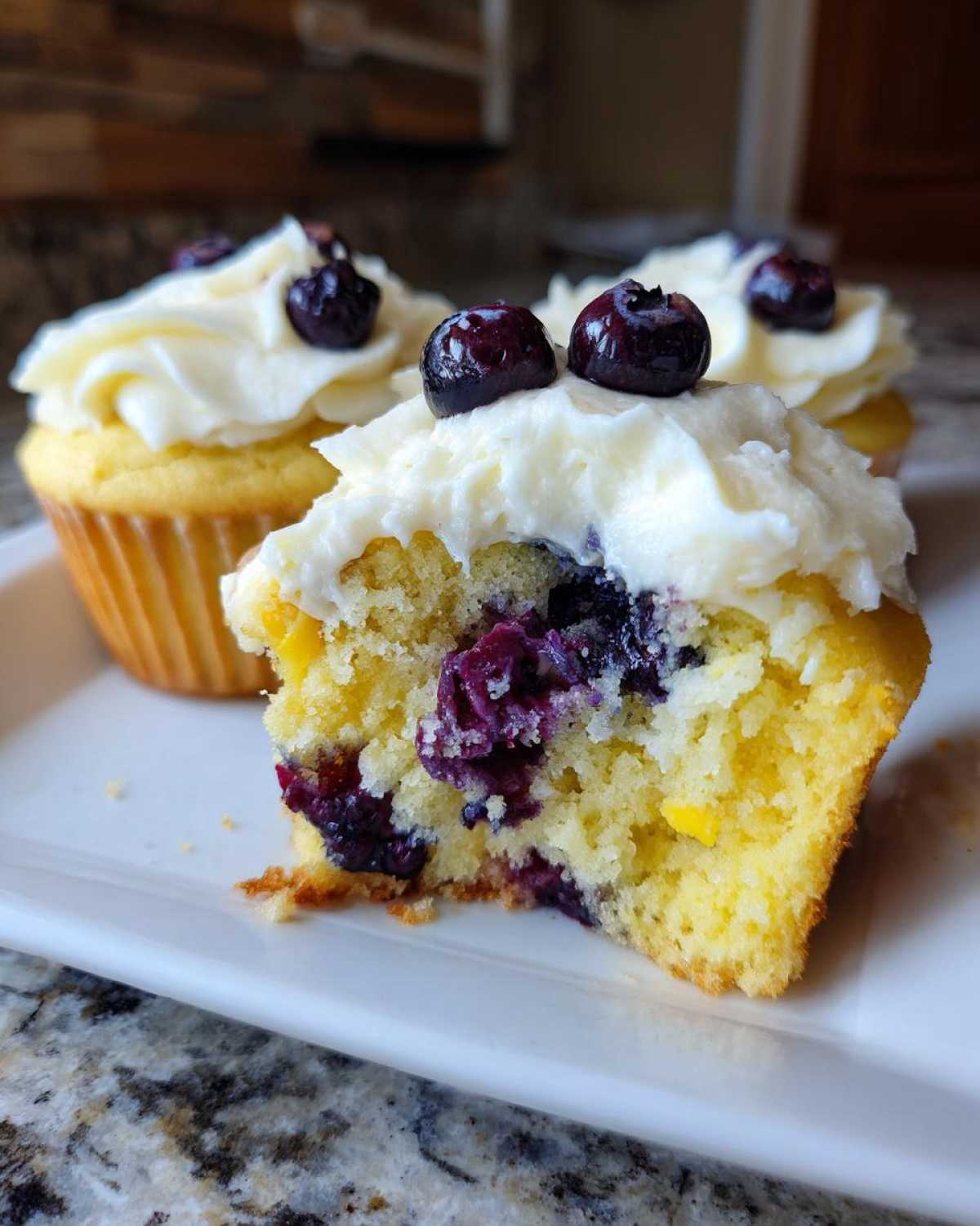 Close-up of a Lemon Blueberry Cupcakes with Cream Cheese Frosting, showing the moist interior packed with blueberries.