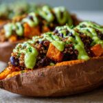 Close-up of a Loaded Veggie Stuffed Sweet Potato topped with quinoa, black beans, and a bright green sauce.