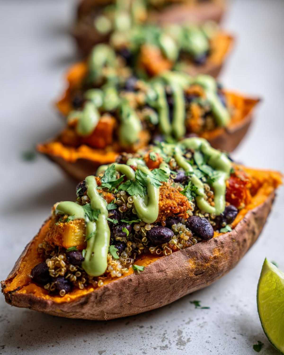 Close-up of a Loaded Veggie Stuffed Sweet Potato topped with quinoa, black beans, and a creamy green sauce.