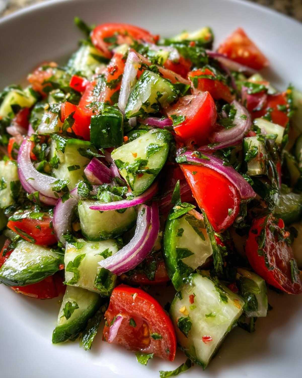 Close-up of fresh Mediterranean Cucumber Tomato Salad with chopped cucumbers, tomatoes, red onion, and herbs.