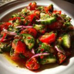 Close-up of a vibrant Mediterranean Cucumber Tomato Salad with fresh herbs and red onion slices.