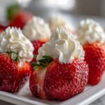Close-up of fresh strawberries stuffed with cheesecake filling and topped with whipped cream, perfect No-Bake Cheesecake Stuffed Strawberries.