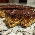 Close-up of a thick No-Bake Chocolate Peanut Butter Oat Bars slice showing the oat base and chocolate topping.