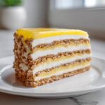 A perfect slice of No-Bake Lemon Icebox Cake showing layers of graham crackers, cream, and lemon filling.
