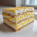 A layered slice of No-Bake Lemon Icebox Cake showing graham crackers, lemon curd, and whipped cream.