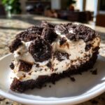 A close-up of a rich slice of No-Bake Oreo Cheesecake showing the creamy filling and dark chocolate cookie crust.