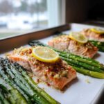 Close-up of baked One-Pan Lemon Garlic Salmon with Asparagus, topped with a lemon slice.