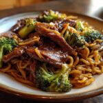 Close-up of savory One-Pot Beef and Broccoli Ramen Noodles coated in a rich brown sauce on a plate.