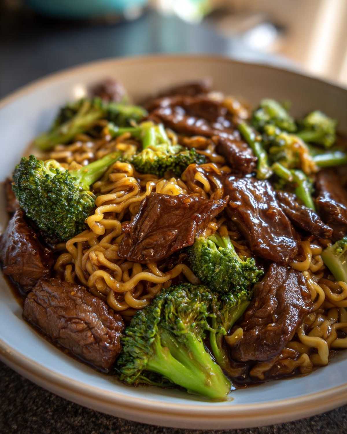 Close-up of a bowl of One-Pot Beef and Broccoli Ramen Noodles coated in a savory brown sauce.