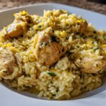 Close-up of a serving of One-Pot Chicken and Rice with Lemon and Herbs, topped with zest and parsley.