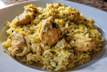 Close-up of a serving of One-Pot Chicken and Rice with Lemon and Herbs, topped with zest and parsley.