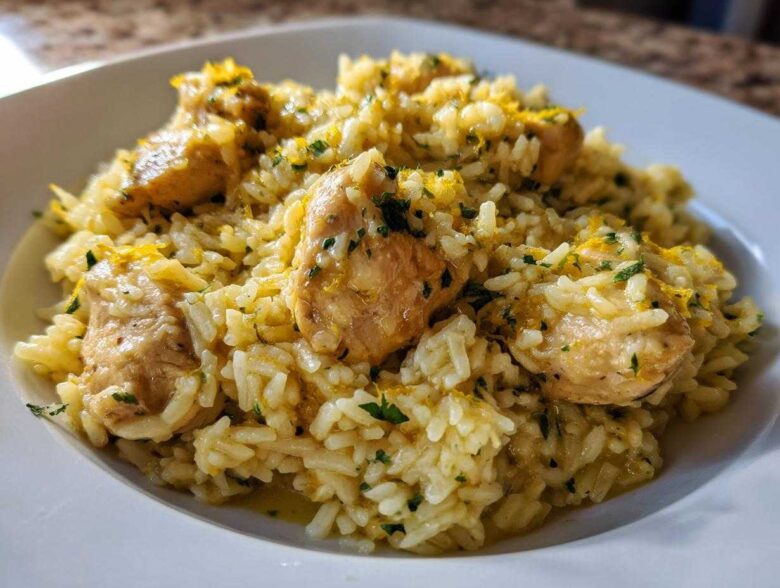 Close-up of a serving of One-Pot Chicken and Rice with Lemon and Herbs, topped with zest and parsley.