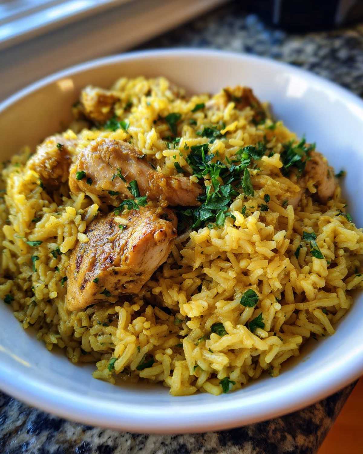 Close-up of a white bowl filled with One-Pot Chicken and Rice with Lemon and Herbs, topped with fresh parsley.