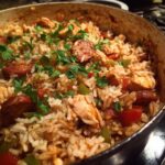 Close-up of flavorful One-Pot Chicken Jambalaya with sausage, chicken, rice, and green peppers, garnished with parsley.