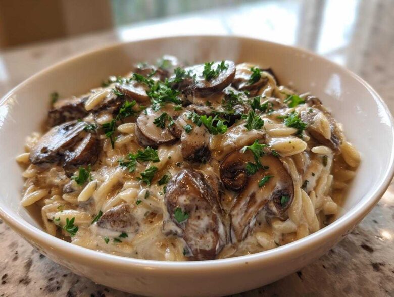 A close-up of a white bowl filled with One-Pot Creamy Mushroom Orzo, topped with sautéed mushrooms and fresh parsley.