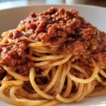 Close-up of a plate of spaghetti topped generously with rich Vegan Lentil Bolognese sauce.