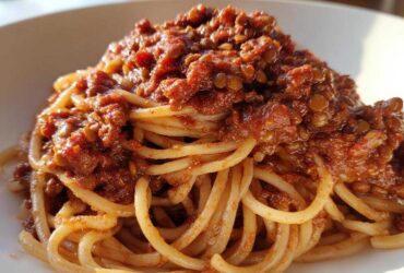 Close-up of a plate of spaghetti topped generously with rich Vegan Lentil Bolognese sauce.