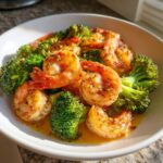 Close-up of plump shrimp and bright green broccoli florets coated in garlic butter sauce from the Sheet Pan Garlic Butter Shrimp and Broccoli.