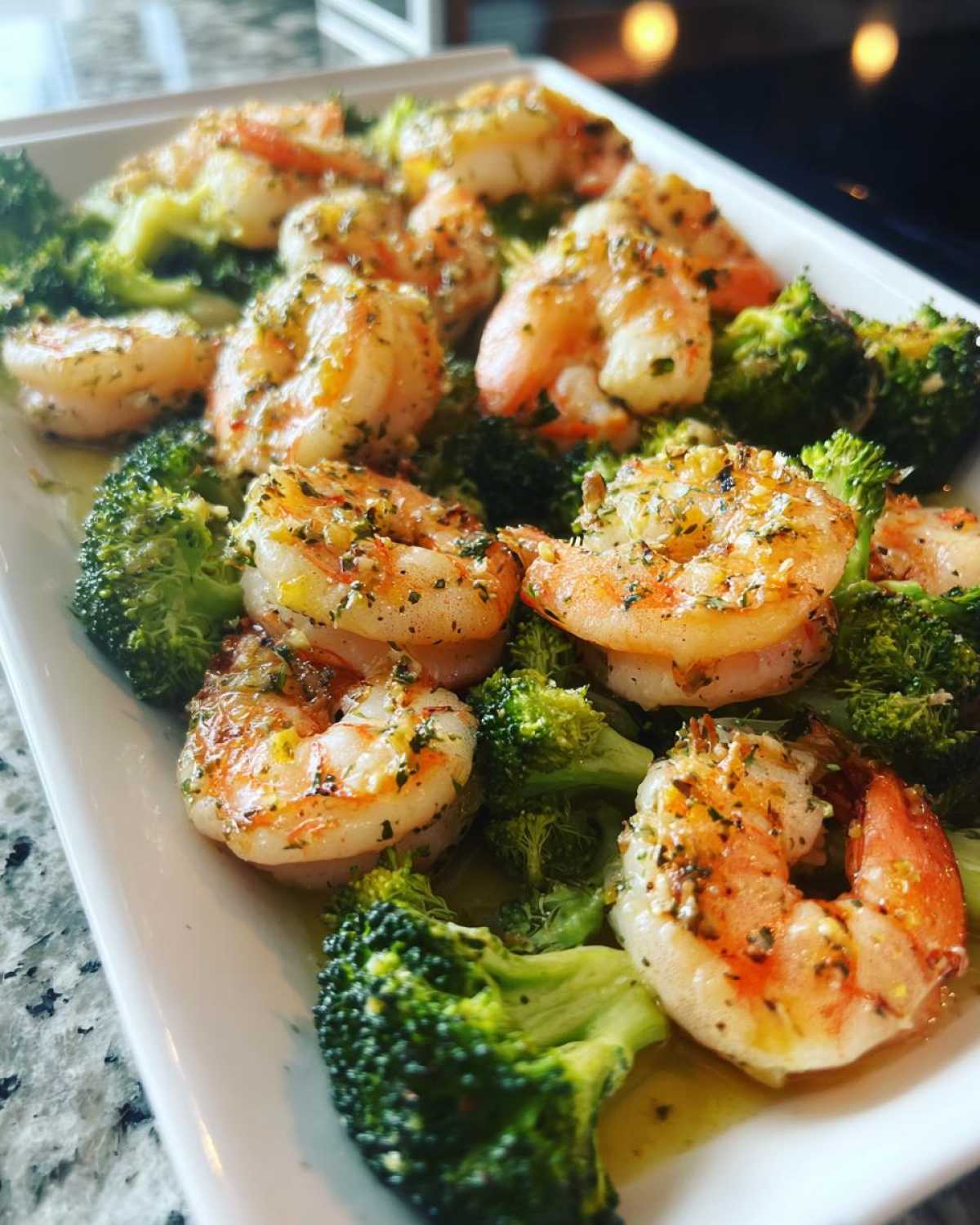 Close-up of cooked shrimp and bright green broccoli florets coated in garlic butter sauce.