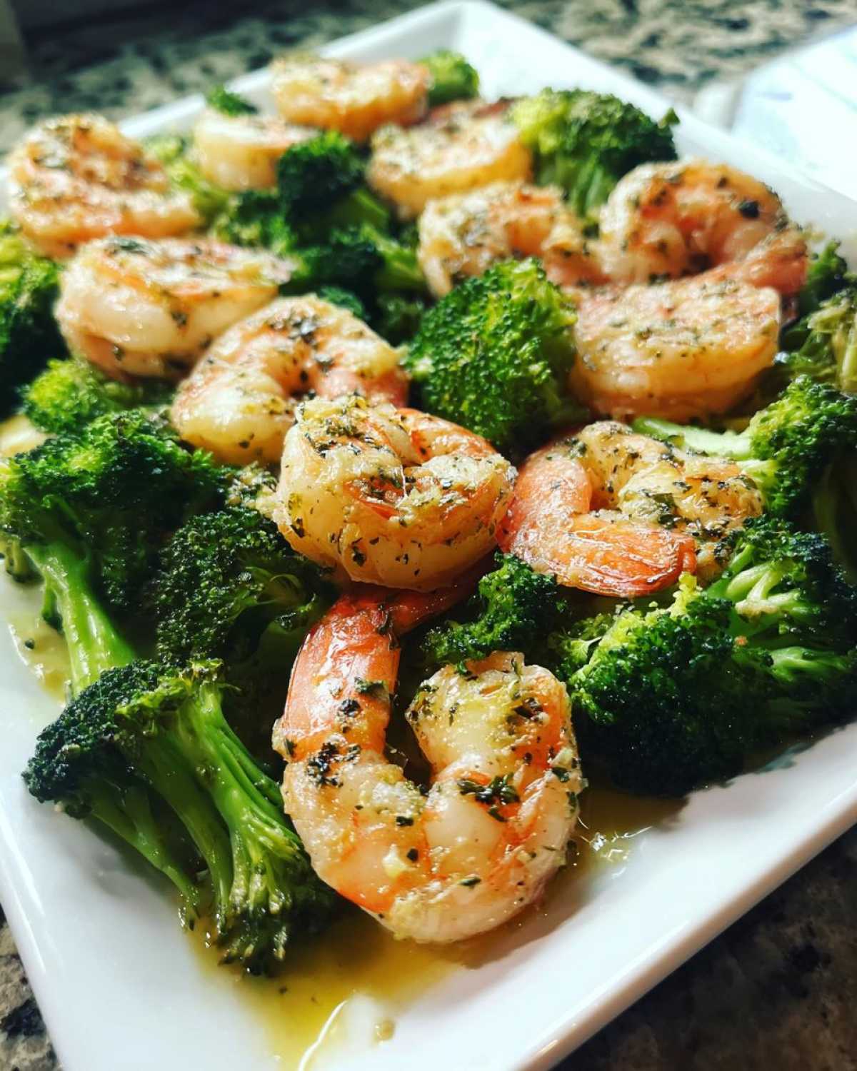 Close-up of cooked shrimp and bright green broccoli florets coated in garlic butter sauce.