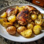 Close-up of crispy chicken thighs and roasted potatoes seasoned with lemon pepper, ready to eat.