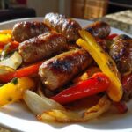 Close-up of grilled Italian sausage links served over colorful roasted peppers and onions, showcasing the Sheet Pan Sausage and Peppers recipe.