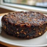 Close-up of a thick, dark, and well-seared Smoky Black Bean Burger Patty on a light gray plate.