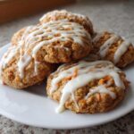 A stack of Soft-Baked Carrot Cake Cookies generously drizzled with white cream cheese glaze.