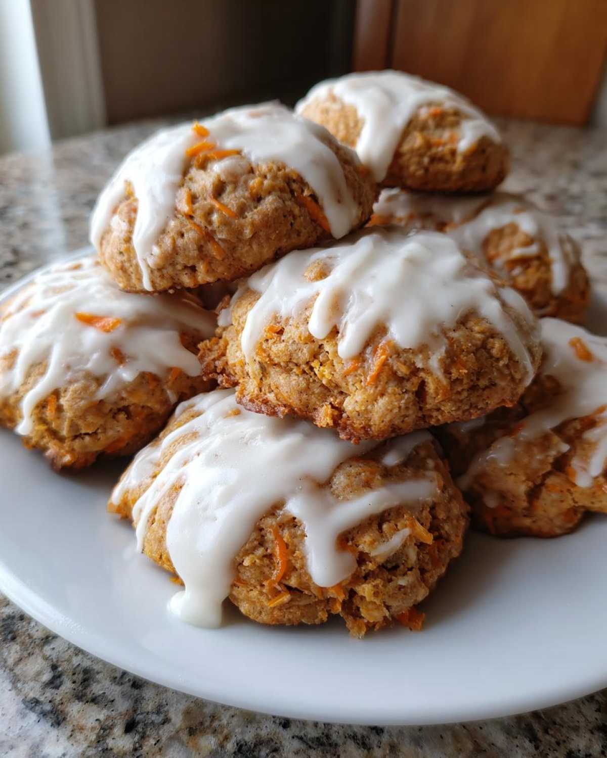 A stack of Soft-Baked Carrot Cake Cookies generously drizzled with thick cream cheese glaze.