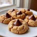 A plate of soft Peanut Butter Blossom Cookies topped with melted chocolate kisses.