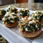 Close-up of baked Spinach and Feta Stuffed Mushrooms topped with crumbled feta cheese.