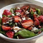 Close-up of a vibrant Spring Mix Salad with Strawberries and Goat Cheese, drizzled with balsamic glaze.