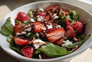 Close-up of a vibrant Spring Mix Salad with Strawberries and Goat Cheese, drizzled with balsamic glaze.