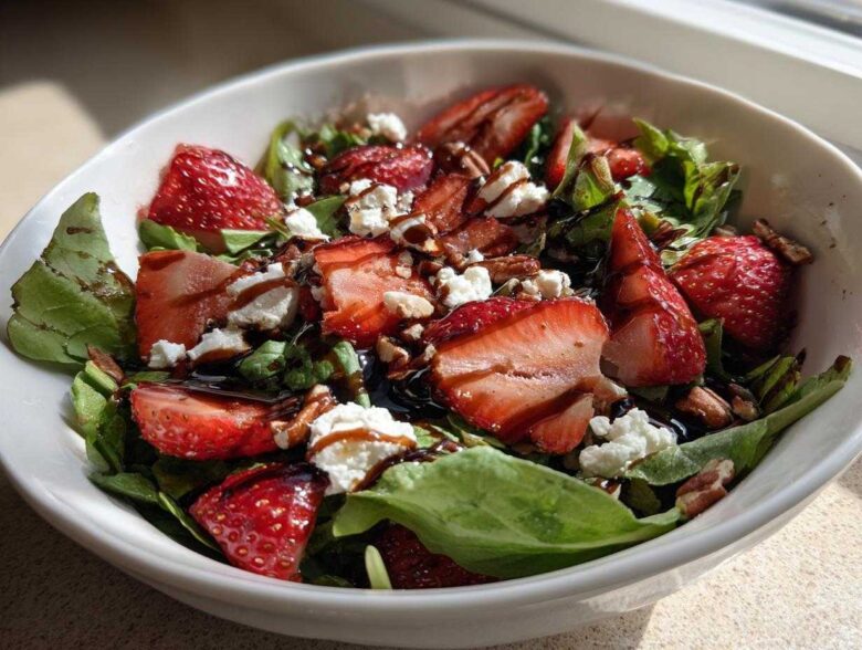 Close-up of a vibrant Spring Mix Salad with Strawberries and Goat Cheese, drizzled with balsamic glaze.