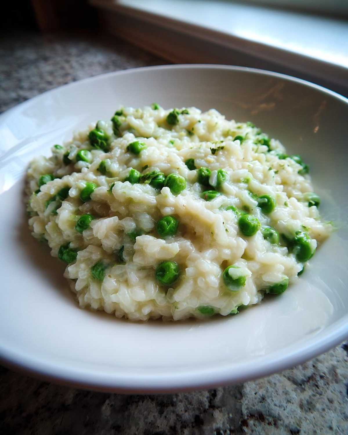 A close-up of creamy Spring Pea and Mint Risotto served in a white bowl, featuring bright green peas.